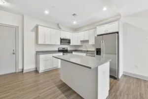 Kitchen with white shaker cabinets and grey quartz worktops at 1580 River St #4D