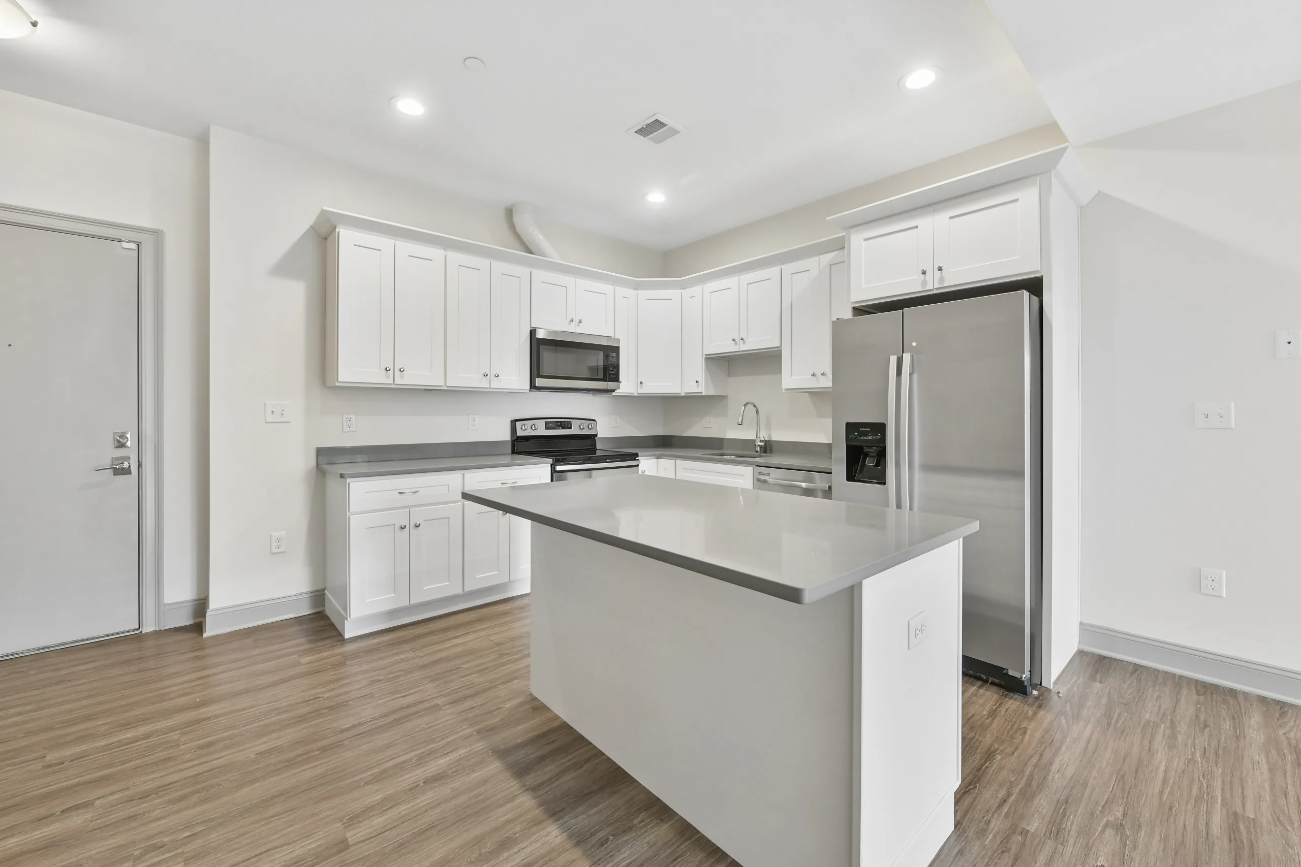 Kitchen with white shaker cabinets and grey quartz worktops at 1580 River St #4D